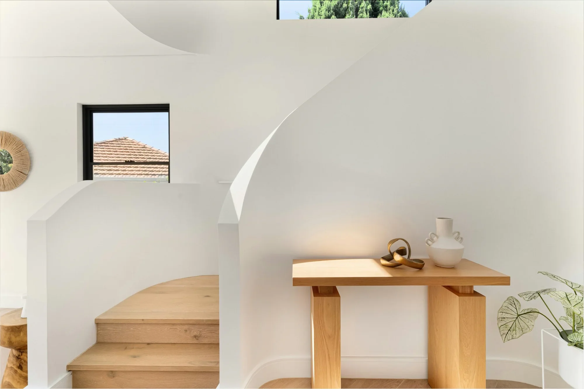 An oak staircase and a small console table in a white plaster hall